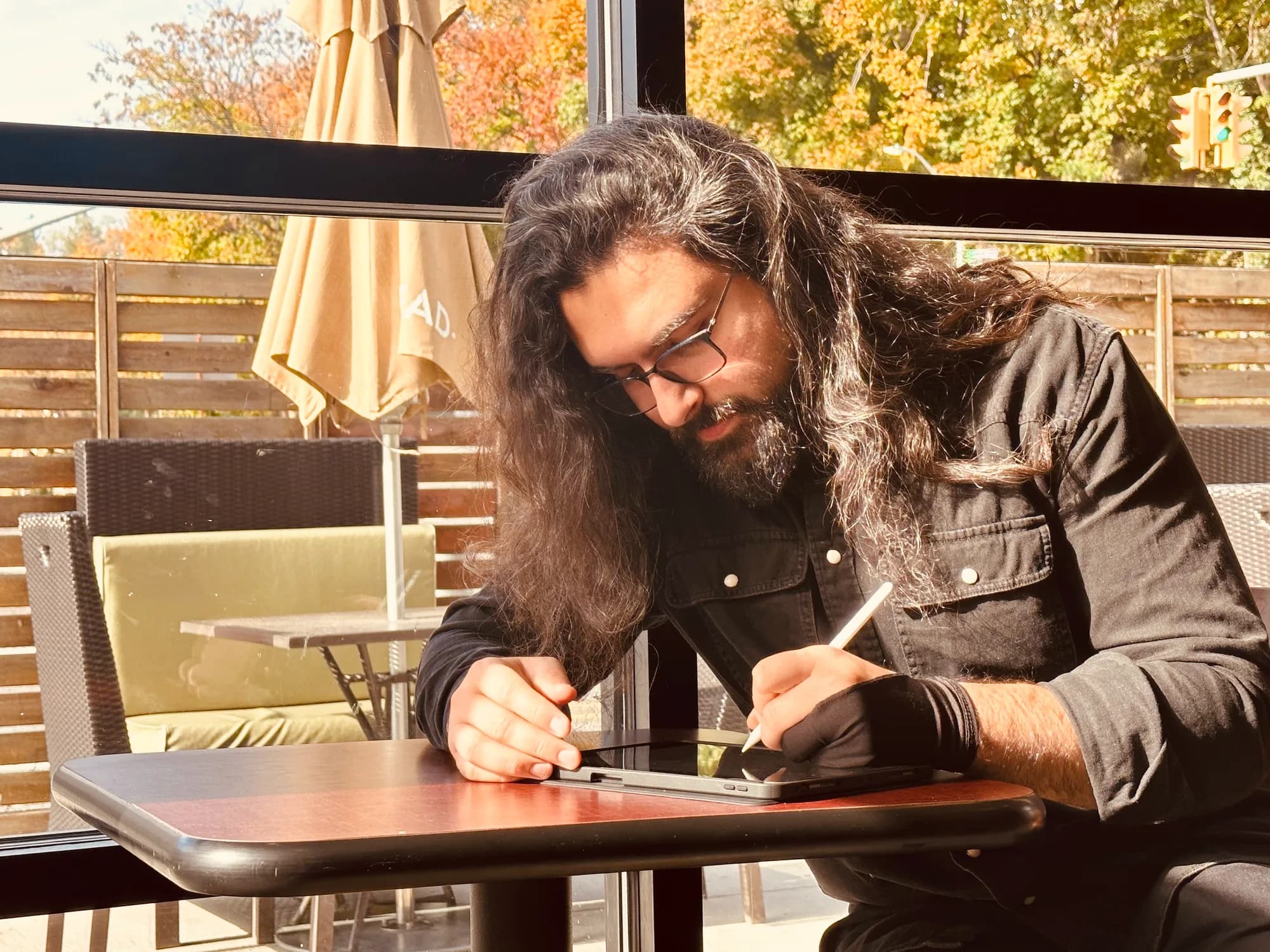 Ali Kutluozen drawing with a stylus at a cafe table